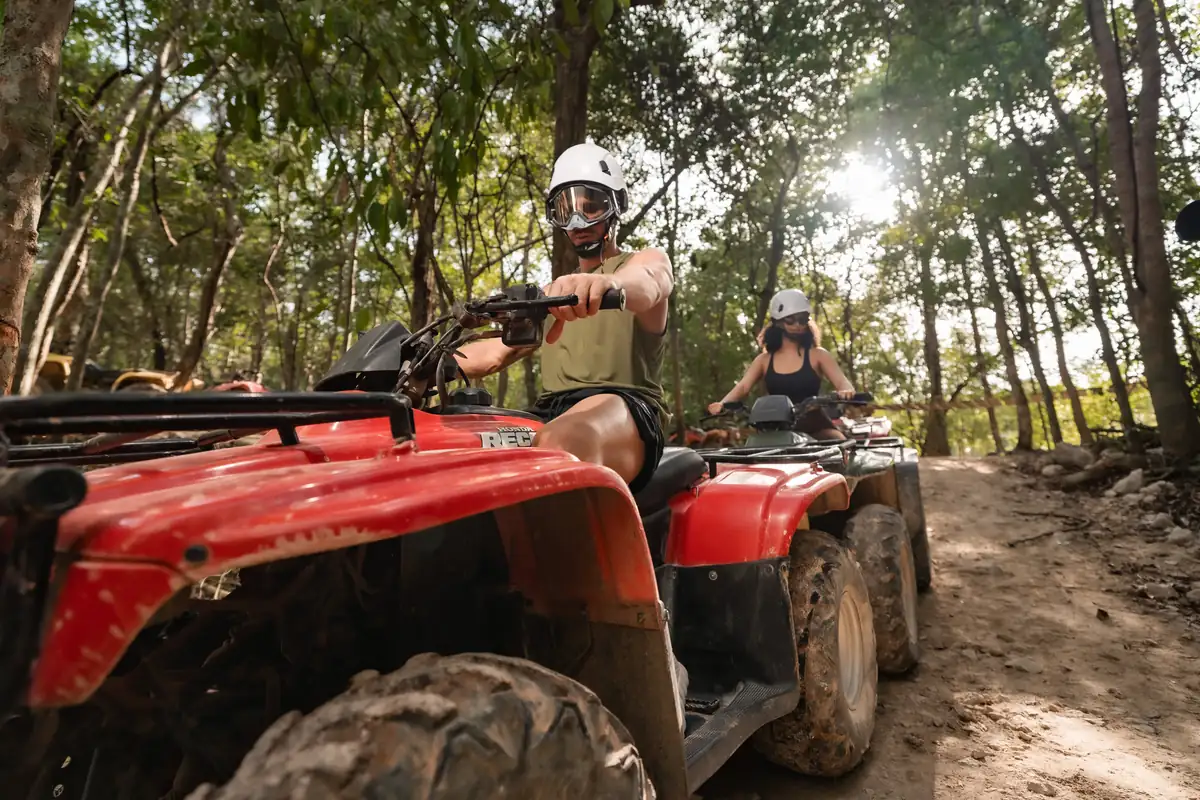 Couple riding a red ATV on a jungle trail near Cancun