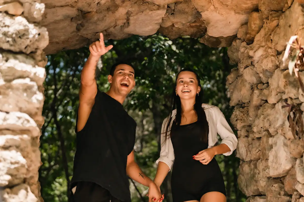 Pareja explorando la entrada techada de una cueva en la selva