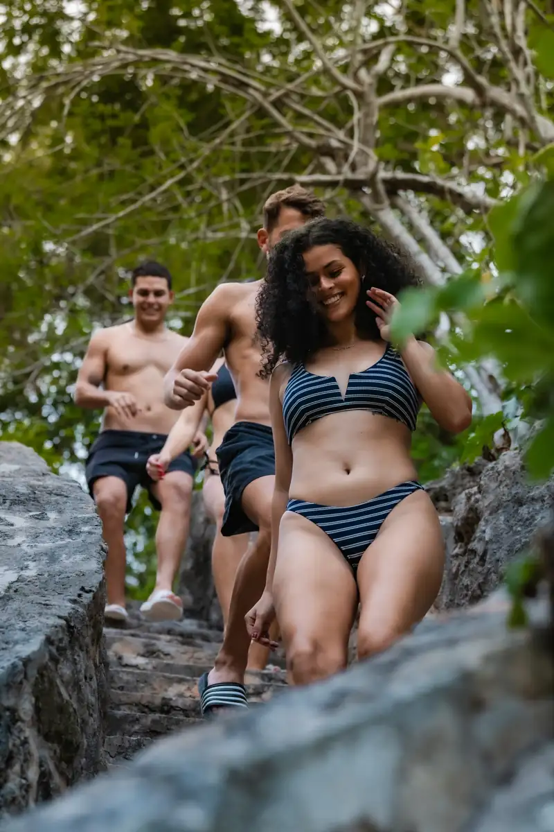 Group of friends walking down stone steps into a cenote