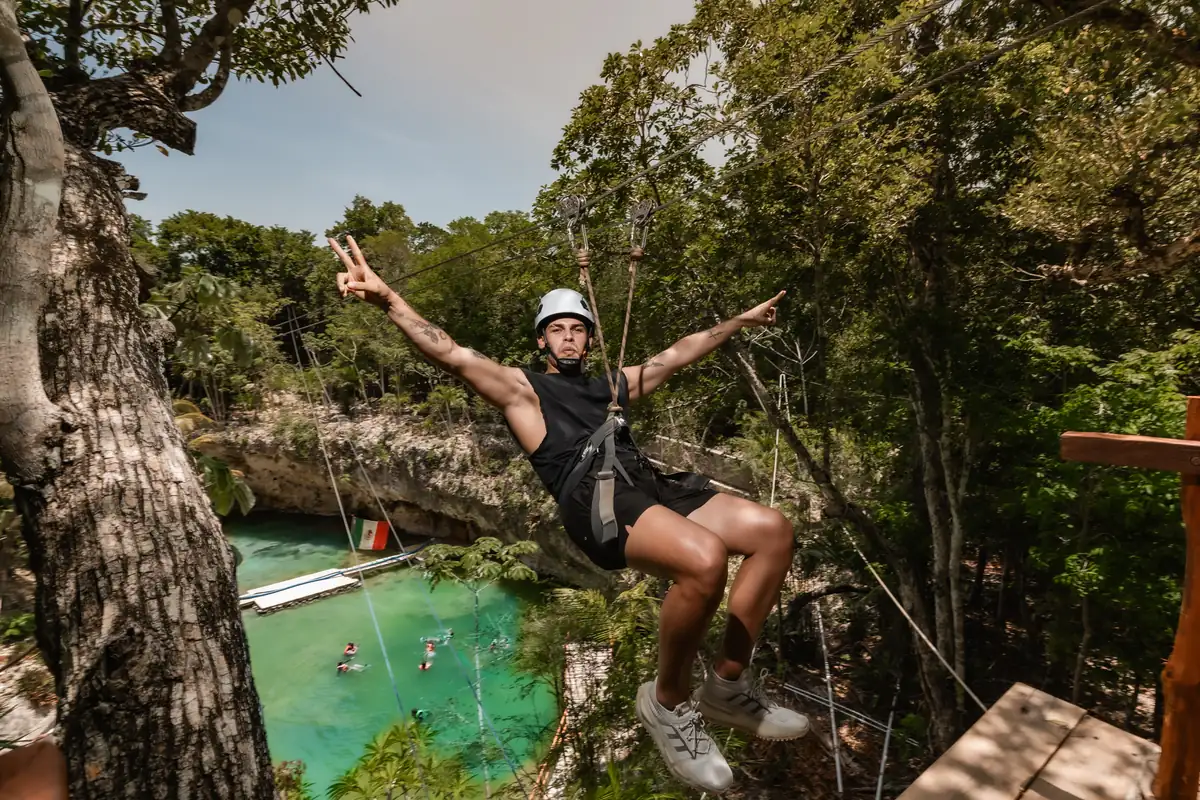 Woman on a zipline above a turquoise cenote in the jungle