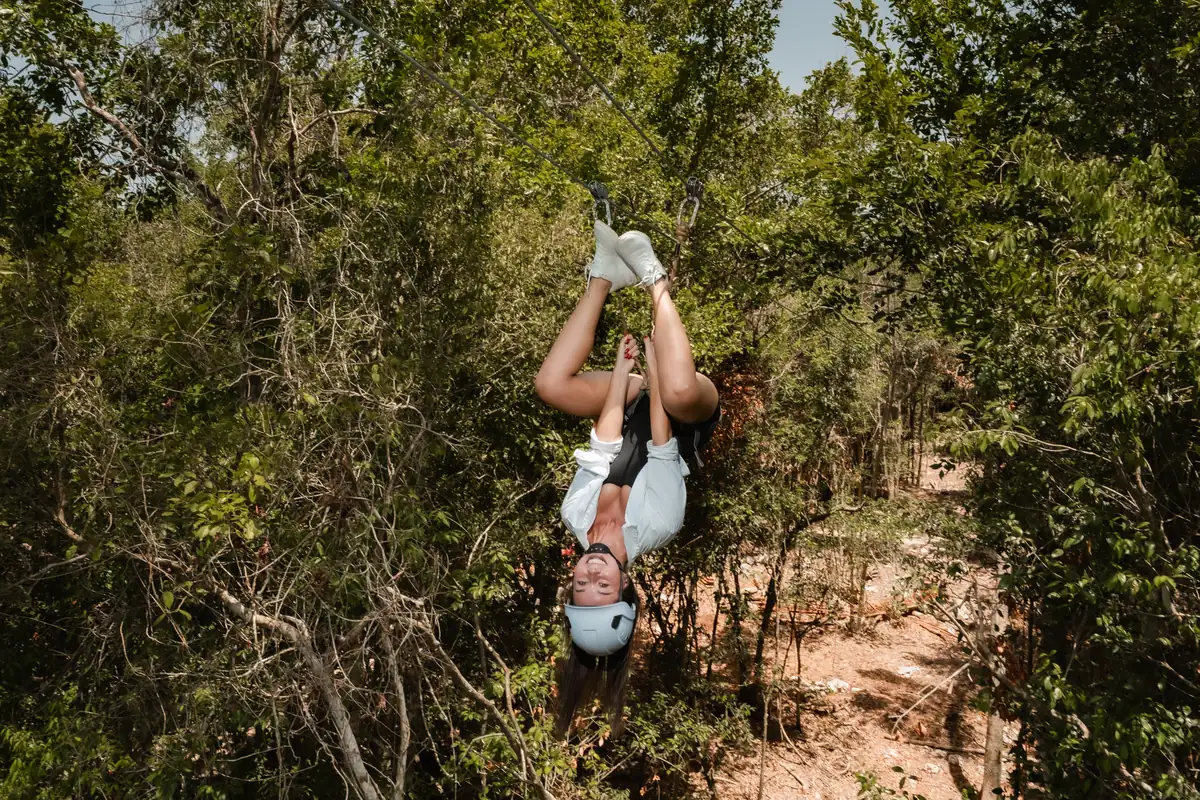Guest hanging upside down on a zipline in the jungle